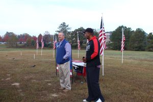 (L) to (R): PDG and Flags For Heroes Co-Chairman Leigh Hudson and Immediate Past President and retired U.S. Marine Michael Sims give tribute to our Veterans on Veterans Day, November 12, 2021.